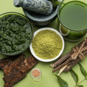 Medicinal Ayurvedic Azadirachta indica or Neem leaves in mortar and pestle with neem paste, juice and twigs, powder and oil, selective focus