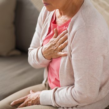 old age, health problem and people concept - close up of senior woman suffering from heartache at home