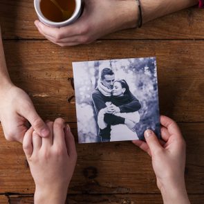 Unrecognizable man holding womans hand. Looking  at their photo. Couple 