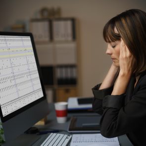 Side View of a Tired Businesswoman Working on her Computer at her Table, Holding her Head with Eyes Closed.