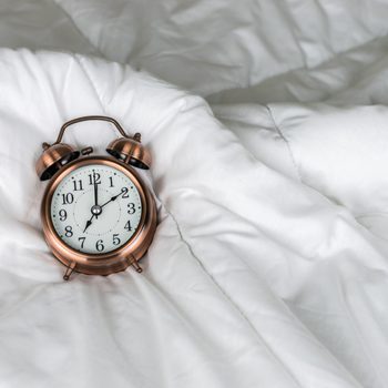 vintage alarm clock on the white bed with copy space.