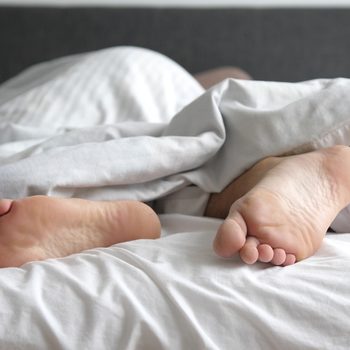 Man sleeping in bed feet relax on holidays. Close up of men feet