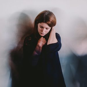 depression concept; long exposure of sad woman against a blank wall