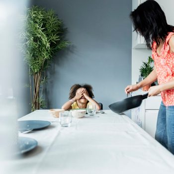 Mother serving meal for daughter sitting at dining table