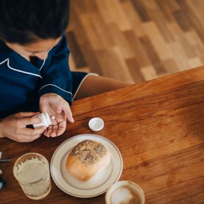 High angle view of woman taking medicine while having breakfast at table