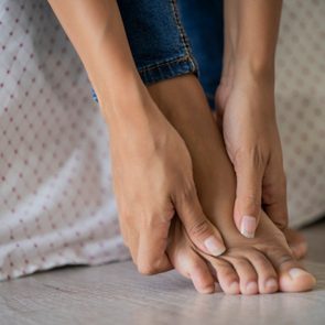 Low section of young woman massaging her foot