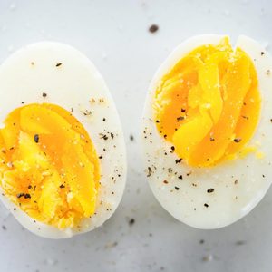 Hard Boiled Egg cut in half with some sprinkled pepper on a marble countertop surface