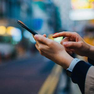 close up on hands of anonymous Woman Using Iphone with blurred city background