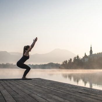 Woman in Yoga Chair Position on Pier Overlooking Lake Bled