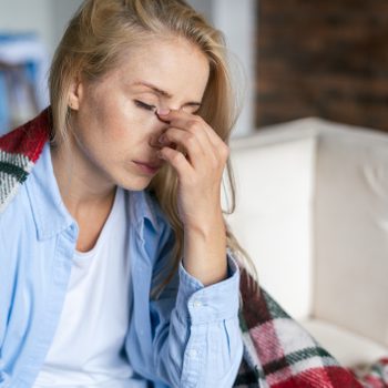 Tired woman with closed eyes touching nose bridge