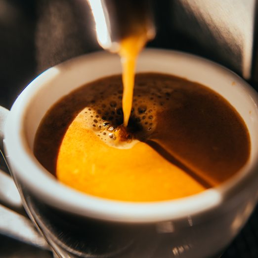 coffee mug filled with coffee underneath coffee machine