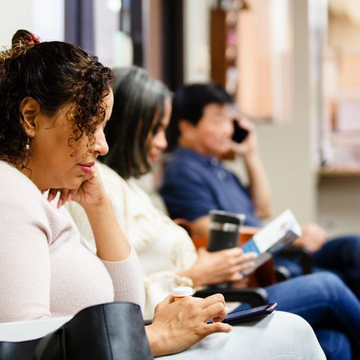 People look at brochure and use smart phones while waiting