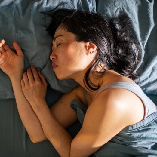 Young Japanese woman sleeping in a bed in a bedroom